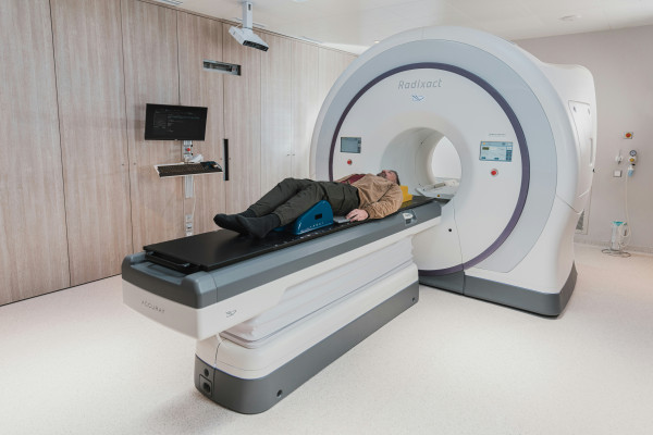 A patient lies on a scanning table, representing the imaging process used to investigate back and leg pain.