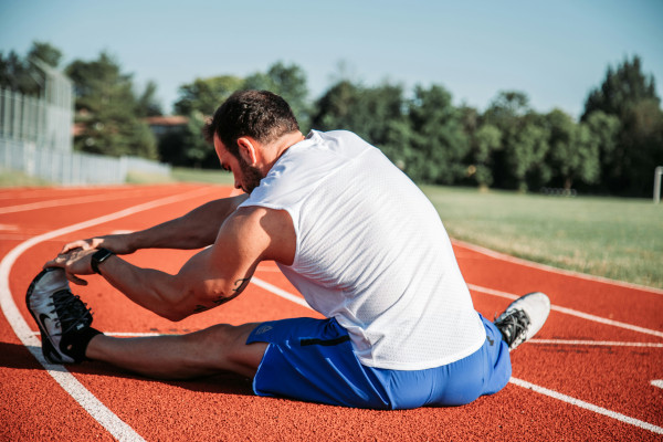 An athlete stretching outdoors, the kind of exercise routine that can plateau without addressing the root cause of muscle weakness