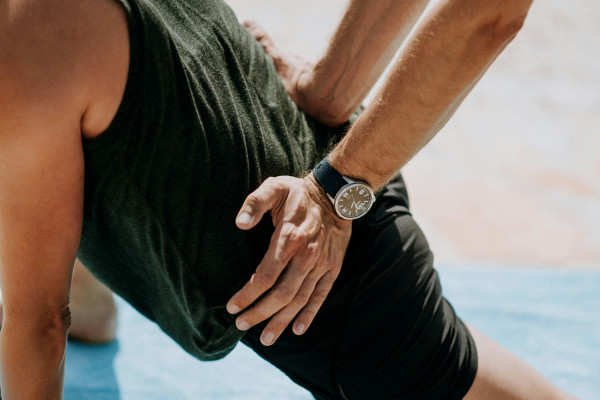 A practitioner using both hands to apply firm pressure to a patient's lower back during a hands-on treatment session.