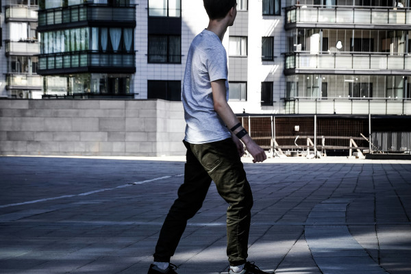 A man walking along a pavement, showing the full-body posture and gait that a pelvic assessment considers