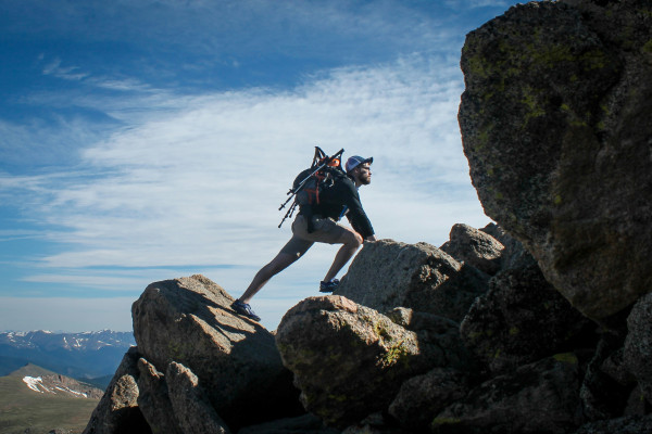 A person climbing a steep rocky mountain slope, showing determination and effort.