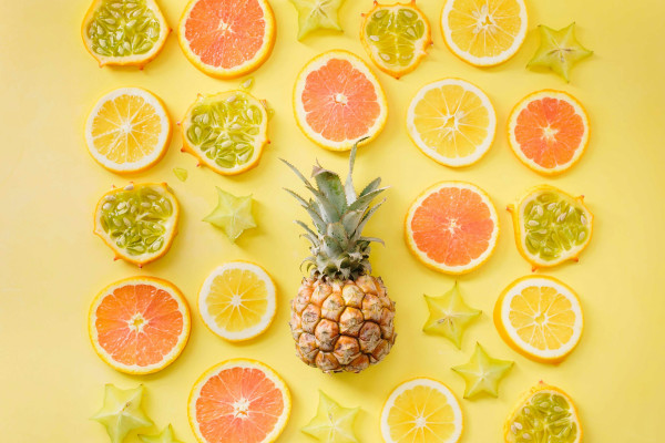 A pineapple surrounded by a colourful array of citrus fruits.