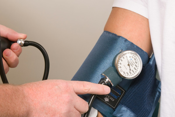 A doctor checking a patient's blood pressure using an arm cuff.