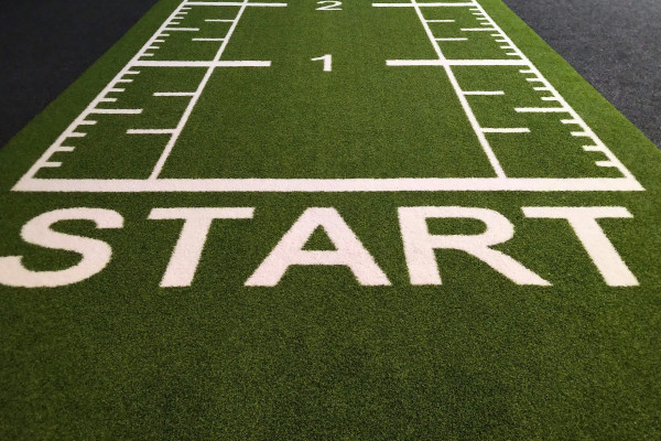 The word START painted in large letters on a football field, symbolising taking action right now rather than waiting