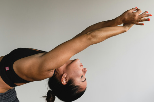 A person stretching their arms outdoors, engaging their whole body in movement.