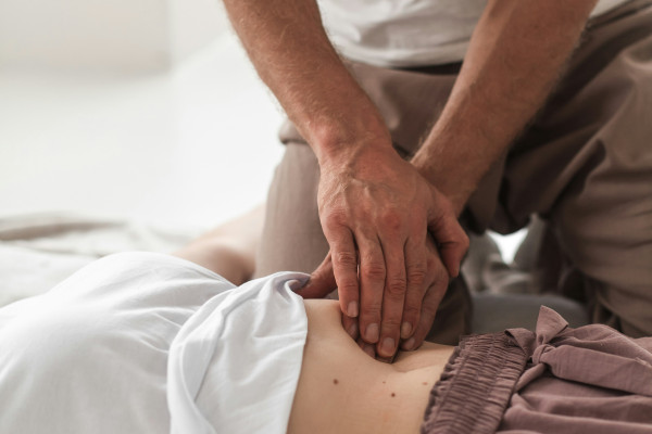 A clinician's hands holding and assessing a patient's leg during an examination.