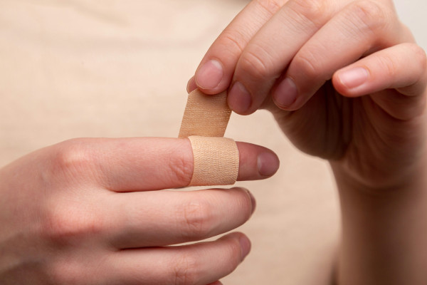A close-up of a person's hand with a small plaster on their finger.