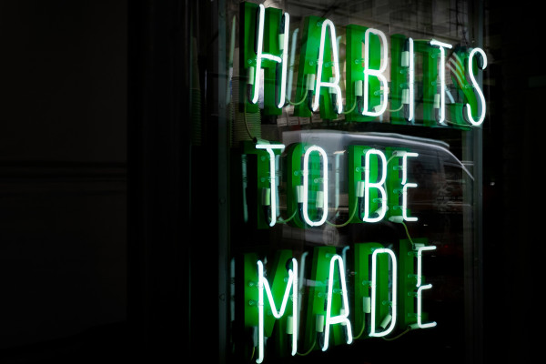An LED sign reading "habits to be made" glowing against a dark background.
