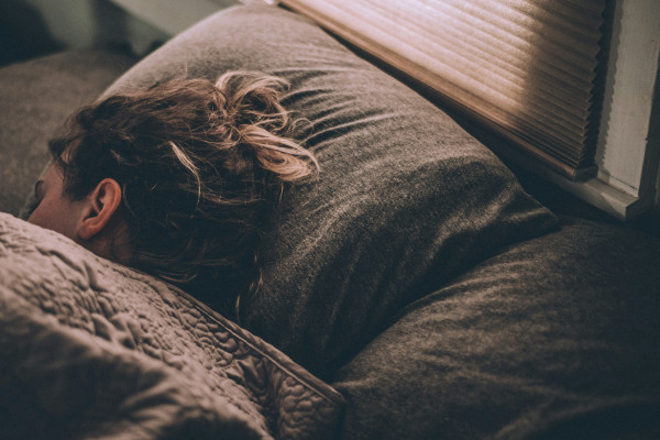 A woman sleeping peacefully under blankets in soft morning light