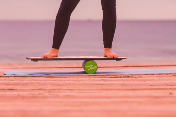 A person standing on a balance board, engaging their core and stability muscles.