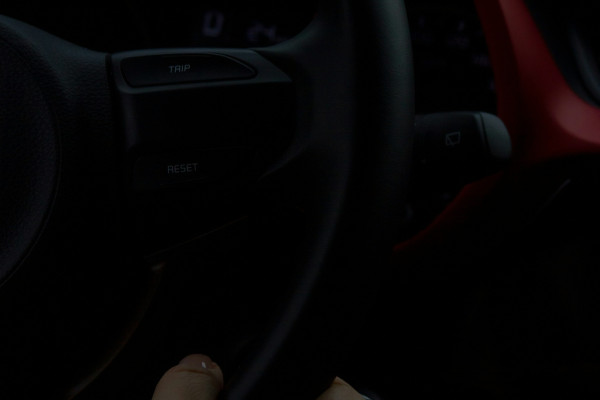 A close-up of a person's hand gripping a steering wheel while driving.