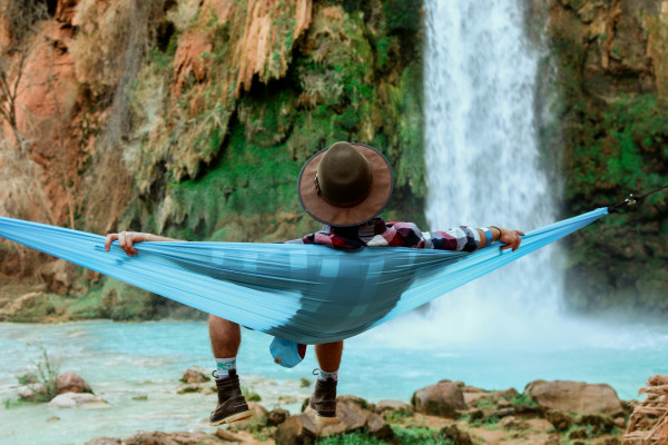 A person relaxing on a hammock near a waterfall, in a state of calm.