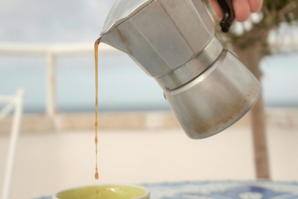 A person pouring coffee into a cup on a table.