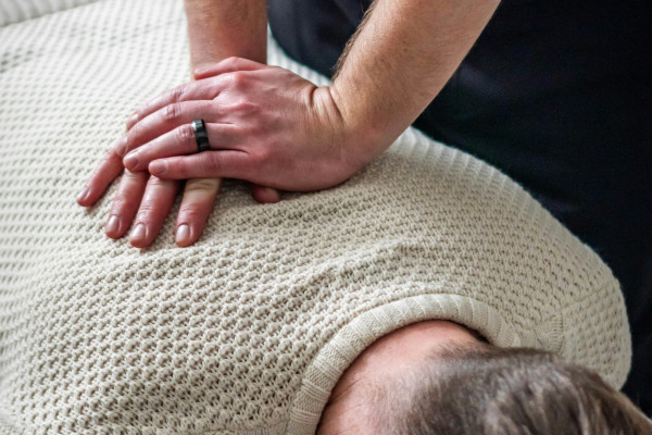 Chiropractor performing a hands-on spinal adjustment on a patient's upper back and neck during a treatment session