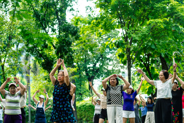 A group of older adults exercise together outdoors in a park, staying active as part of healthy ageing.