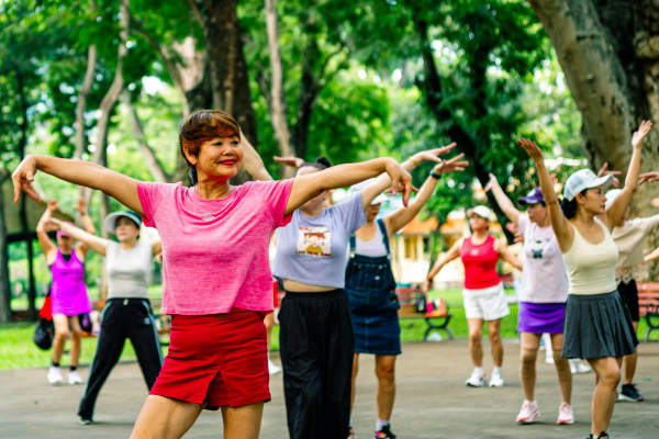 A group of women exercising together outdoors in a park.