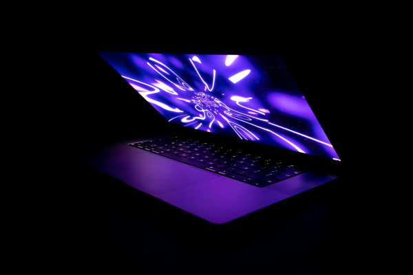 A laptop computer with a glowing screen in a dark room.