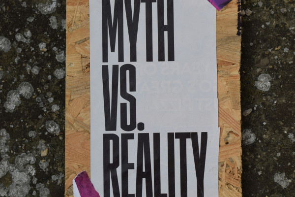 A handwritten note taped to a piece of wood, evoking the idea of separating fact from assumption.