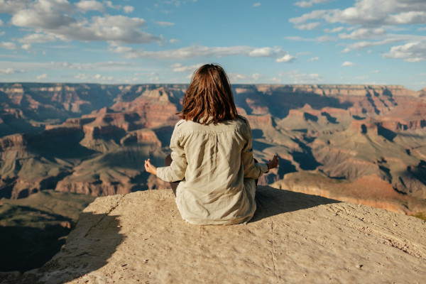 A woman sitting peacefully on a hill, overlooking the landscape.