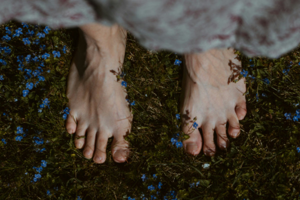 A person's bare feet standing on green grass outdoors.