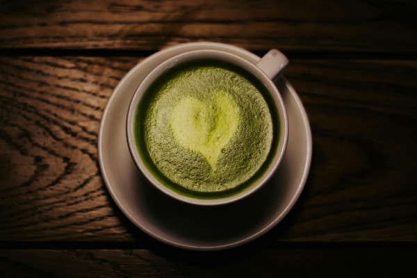 A cup of green tea resting on a wooden table.