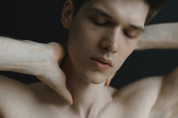 Man holding both hands to the back of his neck, illustrating the habitual neck-cracking motion