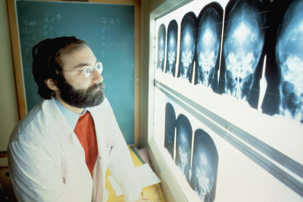 A physician in a white coat reviewing an X-ray image, representing evidence-based medical assessment