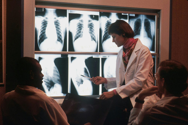 A doctor talking with a patient in front of an x-ray image.