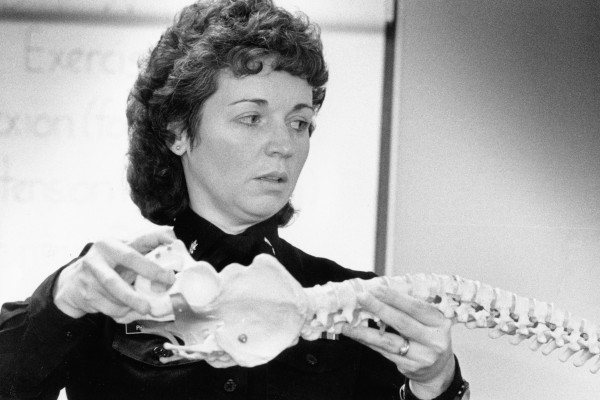 A person holding an anatomical model of the human spine.
