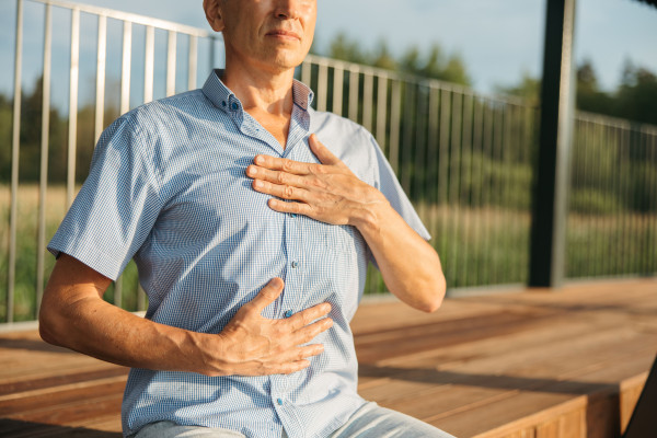 A man practising calm, mindful breathing with hands on his chest outdoors