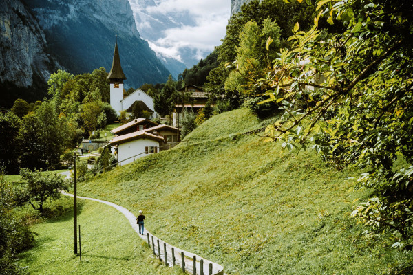 Person walking along a countryside pathway with mountains in the background