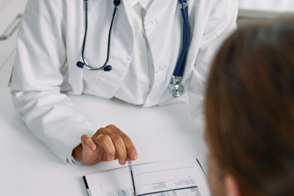 A doctor consulting with a patient in a clinic setting, reviewing a medical chart