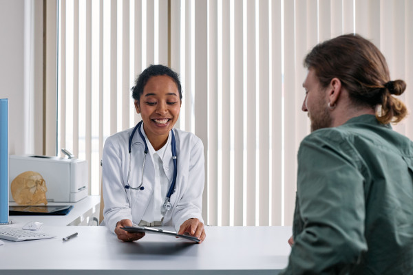 A clinician sitting across from a smiling patient during a friendly consultation in a bright clinic room