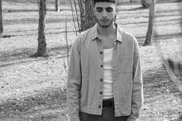 Man standing still outdoors with his eyes closed, in a calm, focused pose