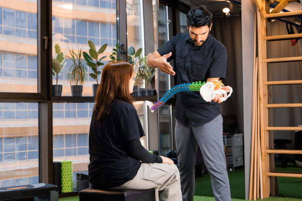 Chiropractor using a spine model to explain anatomy to a patient