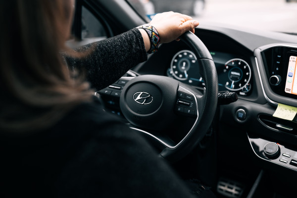 Woman sitting in a car, hands near the steering wheel and dashboard