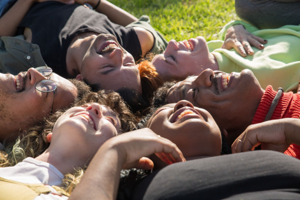 Diverse group of friends smiling and lying together on grass outdoors