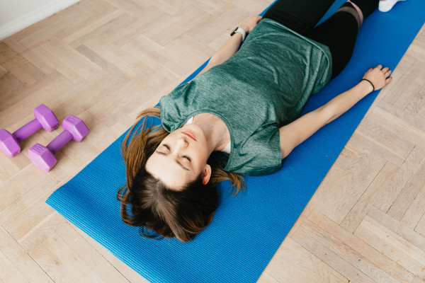 Woman lying on a yoga mat with eyes closed, practicing relaxed breathing
