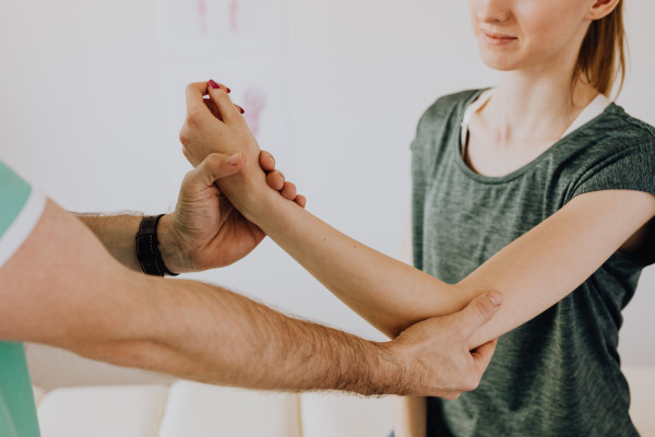 Chiropractor testing a patient's arm and joint movement during a diagnostic assessment