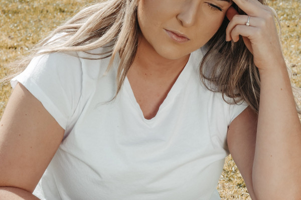 Woman sitting outdoors holding her head during a migraine episode