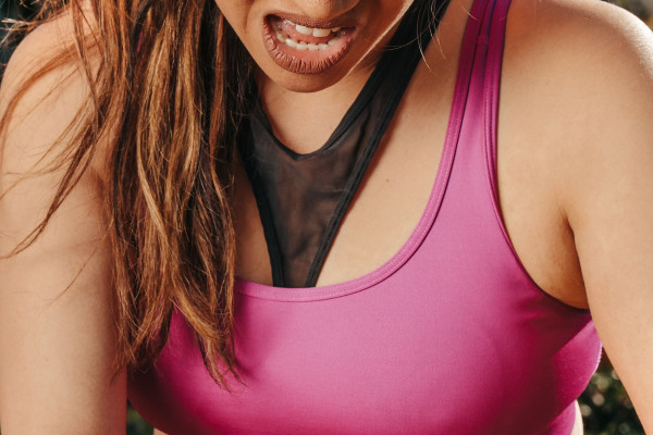 Woman in sportswear holding her knee in pain during outdoor exercise.
