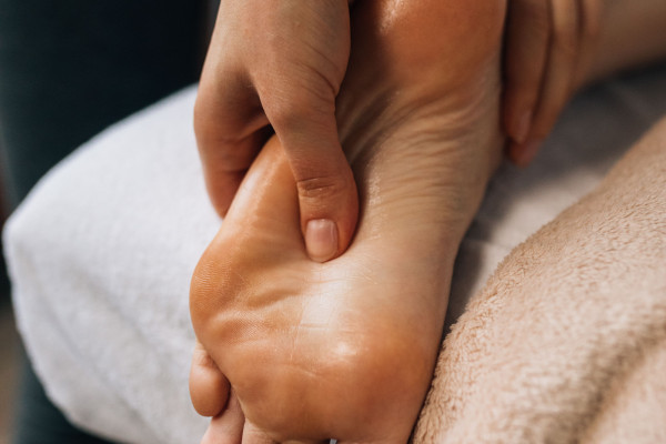 Hands gently massaging a bare foot indoors