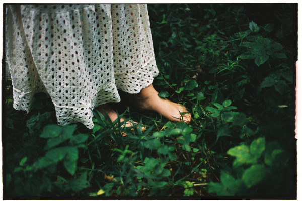 Woman standing barefoot on lush green grass outdoors