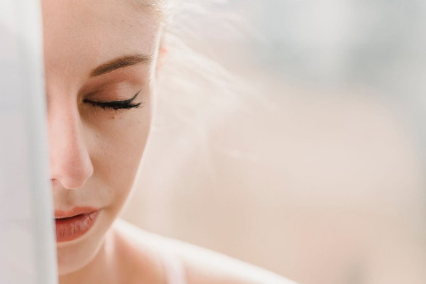 "Close-up of a woman's face partially obscured, eyes closed in a calm expression