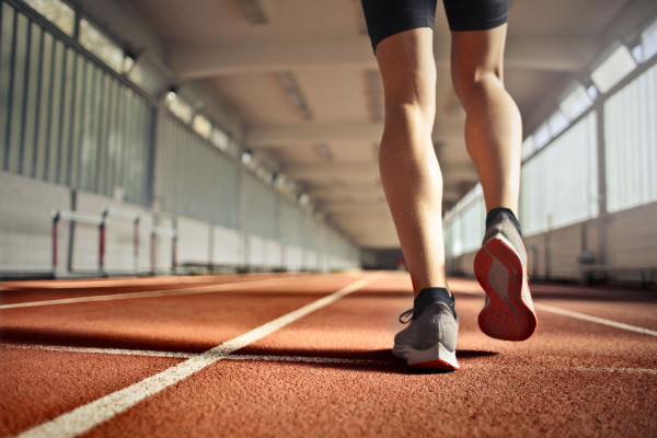 Close-up of an athlete's legs and running shoes on an indoor track, mid-stride