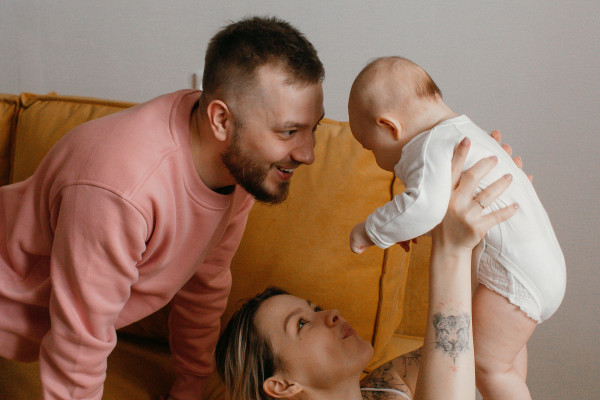Happy parents playing with their baby together at home on the sofa