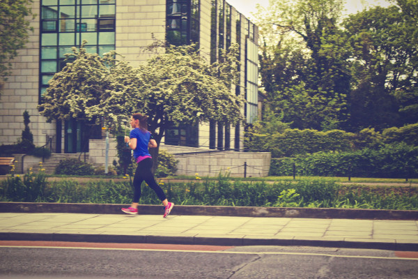 Woman running along a tree-lined city street during the day