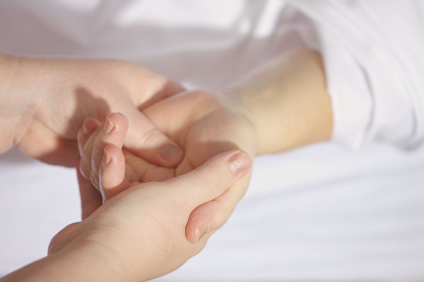 Close-up of a gentle hand massage, hands clasped in a calm therapeutic setting