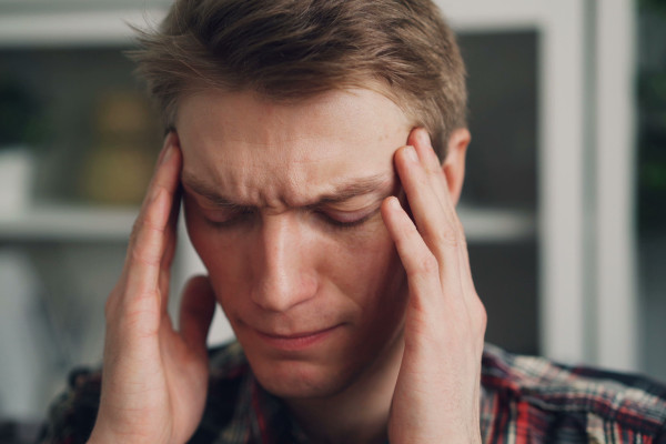 Man rubbing his temples with a worried, tired expression indoors