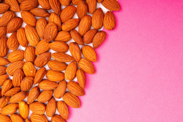 Close-up shot of almond nuts arranged on a pink surface